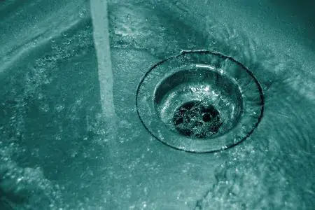 Water going down a drain in a stainless steel sink.